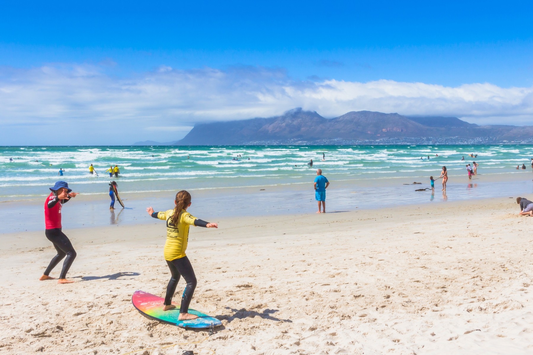 Child learning to surf during December holidays at Muizenberg beach