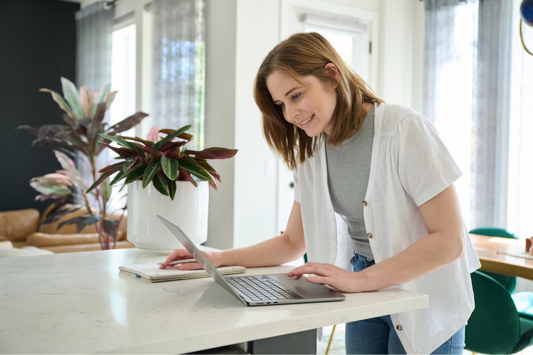 Woman working on her computer in her kitchen setting up short-term rental listing on booking platform