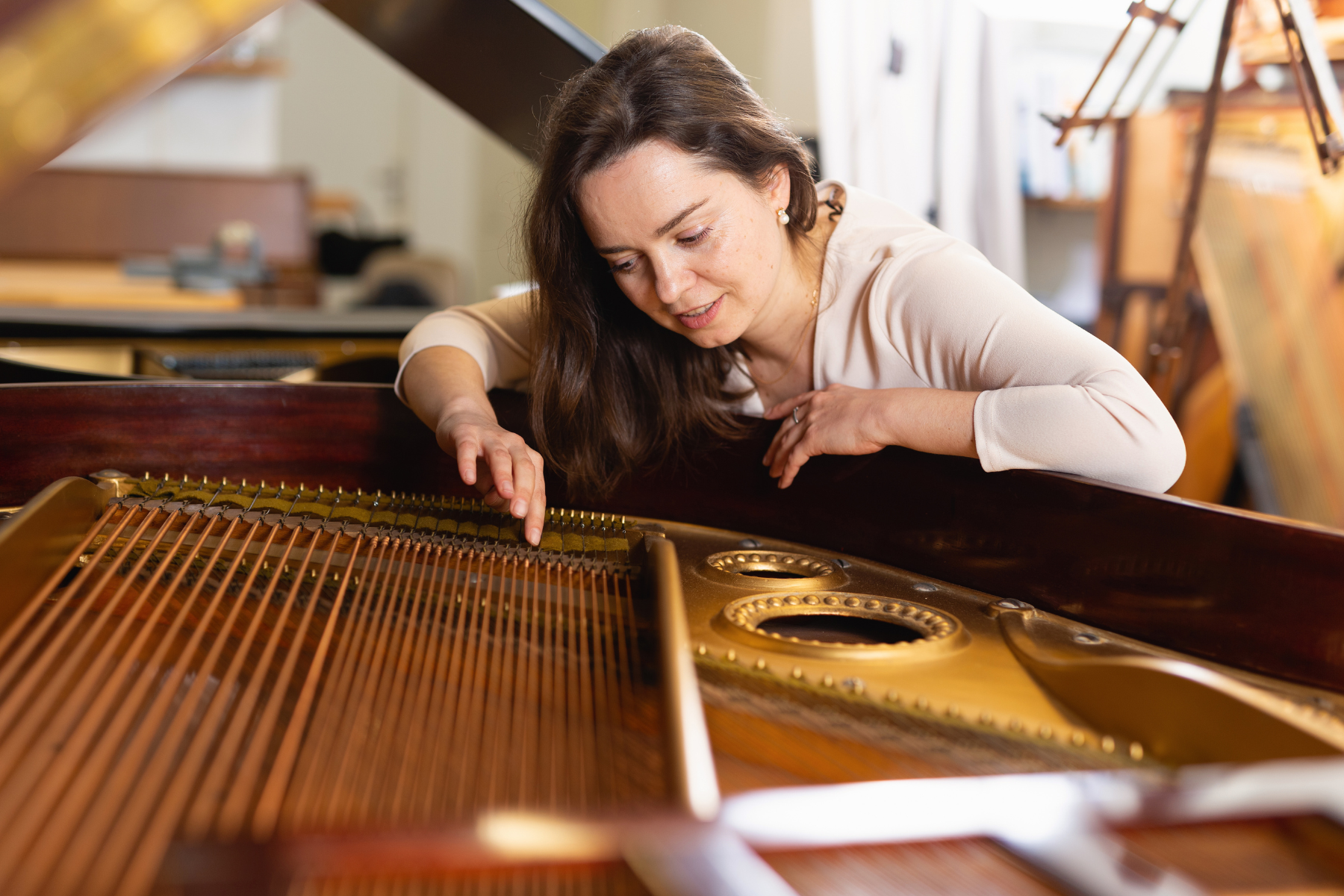 Woman buying second-hand piano assessing the strings