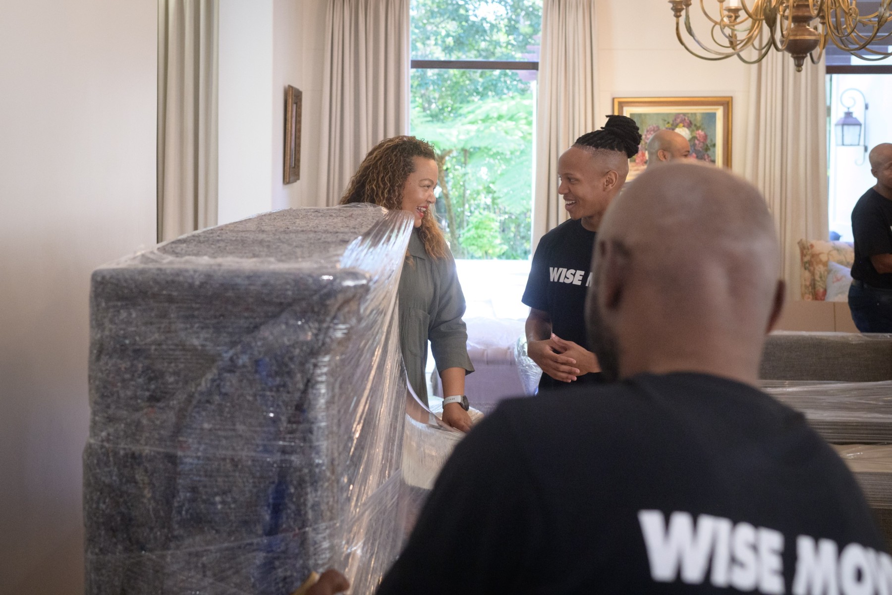 Professional piano movers wrapping and moving upright piano